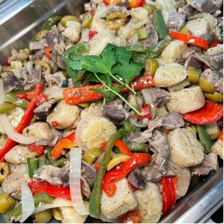 Guineitos en escabeche — green bananas with onions and peppers in a steam-table pan