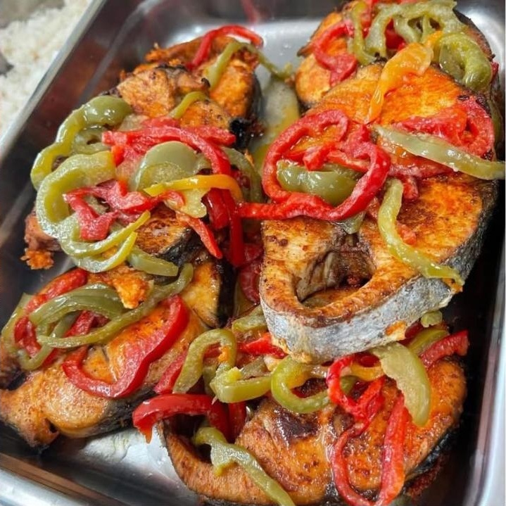 Salmon steaks in a steam-table pan under red and green peppers